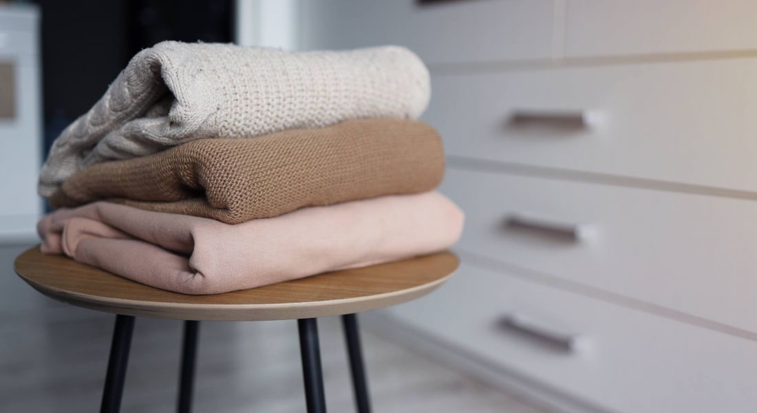 Stack of cozy knitted sweaters on a wooden table