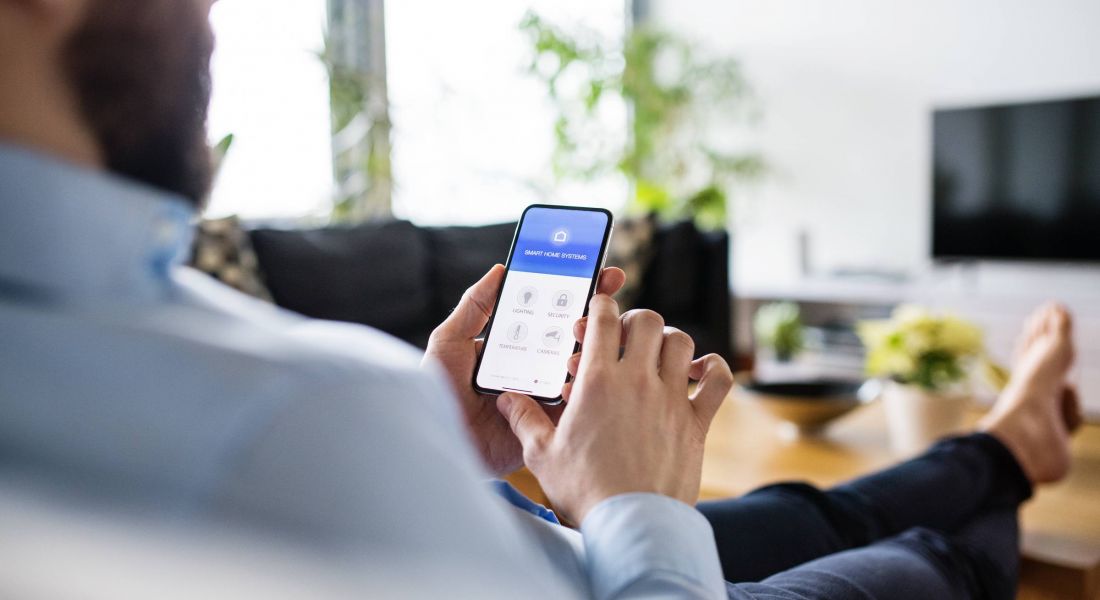 A man holding a smartphone with smart home screen