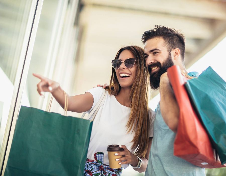 Beautiful couple enjoy shopping together and holding shopping bags and coffee
